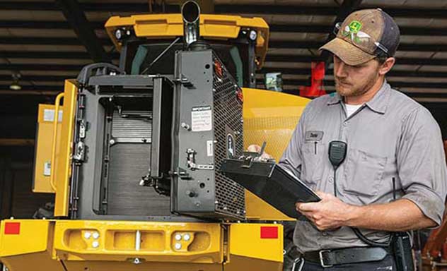 Technician with clipboard inspects a loader