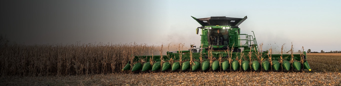 John Deere Harvester harvesting wheat during sunset