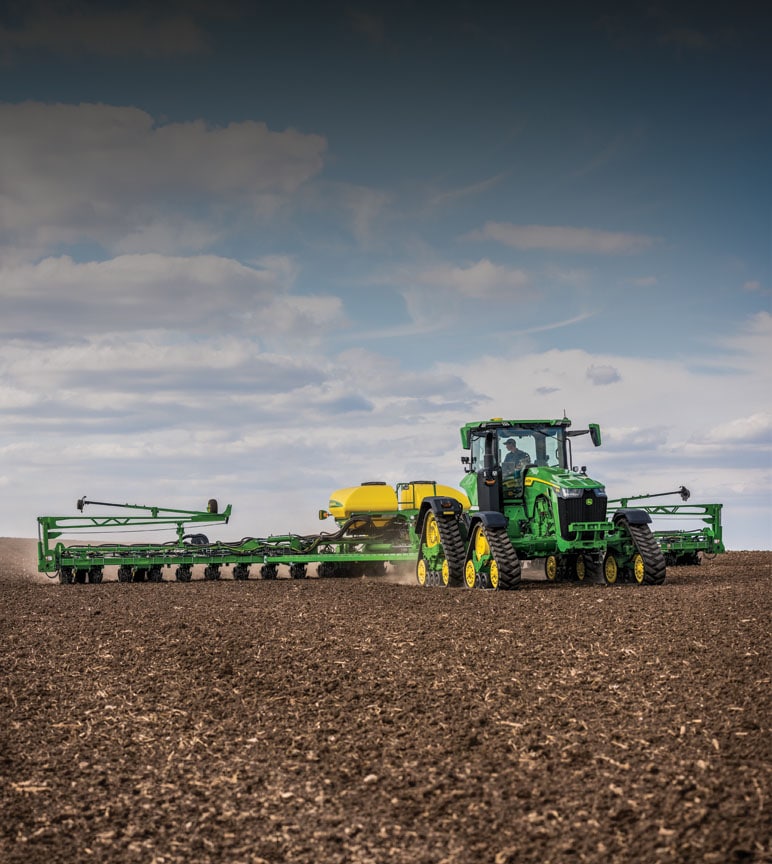 Autonomous John Deere 8RX Series tractor spraying a field.
