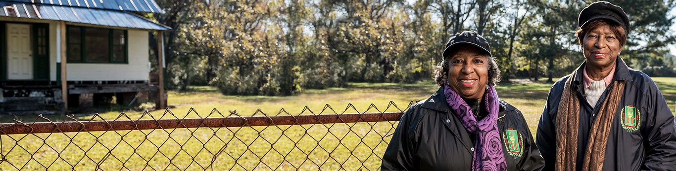 Two black female farmers pose on their land in support of Center for Heirs' Property Preservation.