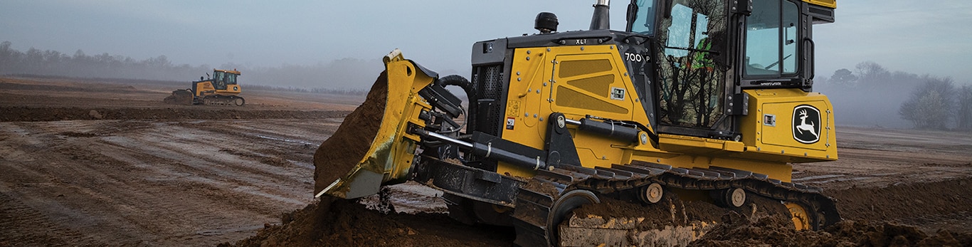 700 P dozer on a dirt mound with another dozer out in the distance pushing dirt.