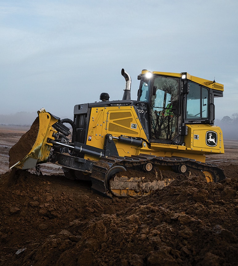700 P dozer on a dirt mound with another dozer out in the distance pushing dirt.