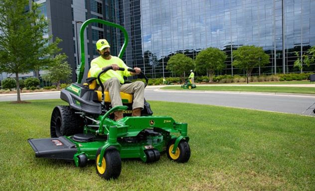 Professional landscaper mowing grass on a commercial Z900M Ztrak mower at an office building.