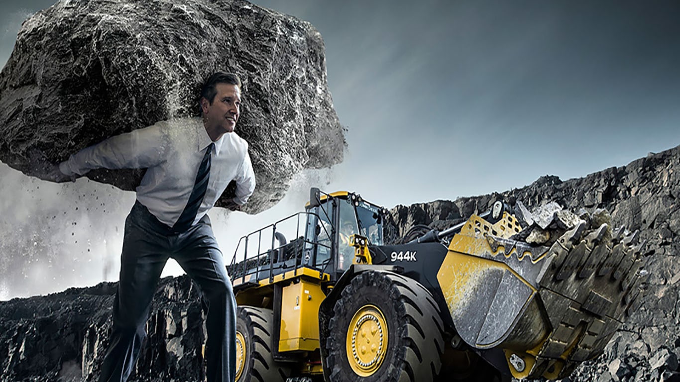 John Deere 944K heavy wheel loader lifting a load a rocks and a man lifting a boulder. 