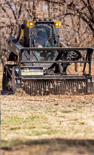 A John&nbsp;Deere 335 P-Tier CTL equipped with an MK76 mulching head navigates through an autumn forest