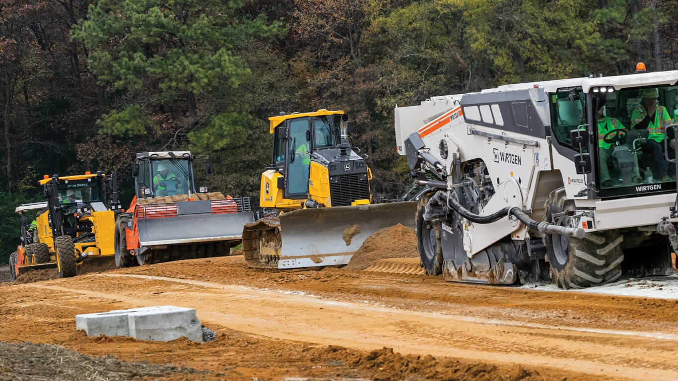 A lineup of Wirtgen and Deere machines working on road construction.