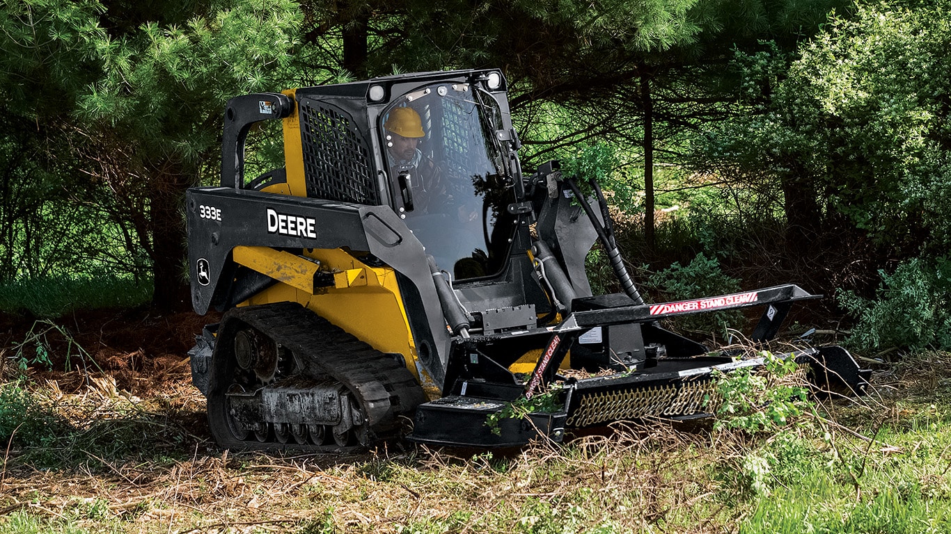 333E Compact Track Loader with rotary cutter attachment working in the woods