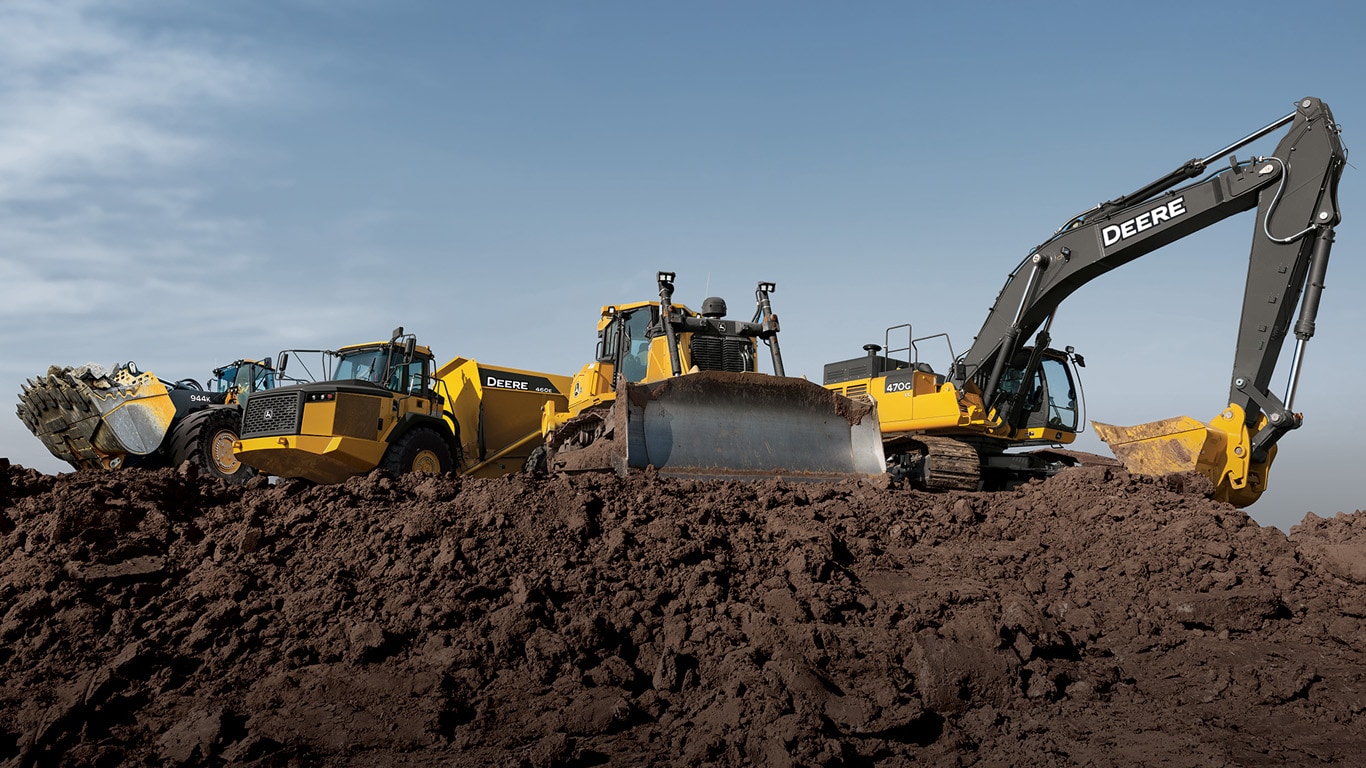 large dozer climbs a dirt pile while a large excavator loads a dump truck