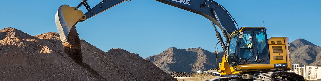 A John Deere 135G Excavator at work on a commercial building job site.