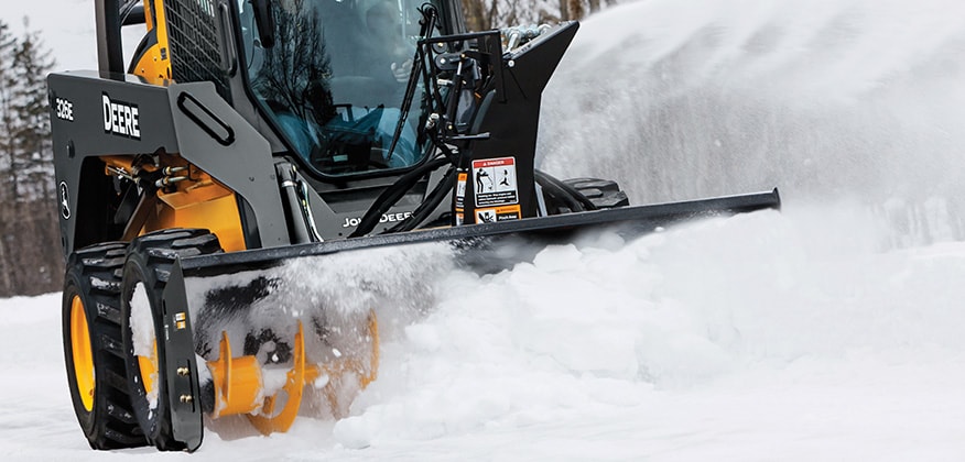 Carretilla Elevadora 326E con un accesorio Soplador de Nieve que sopla nieve de una carretera