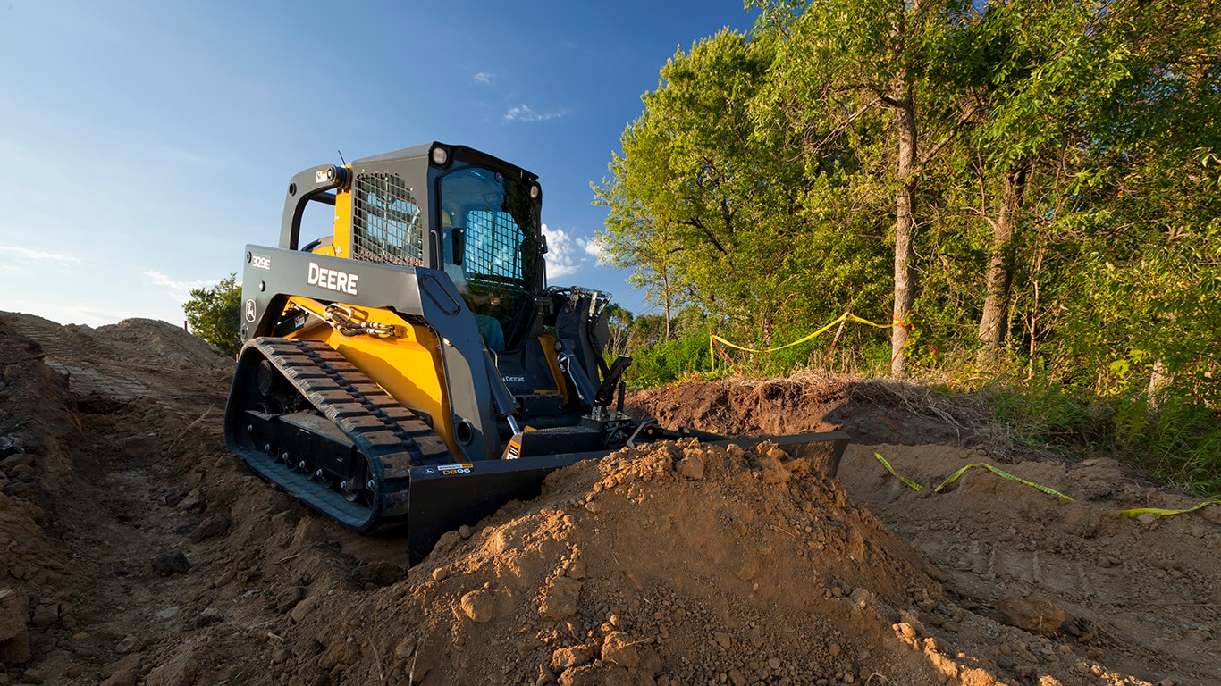 323E Compact Track Loader with Dozer Blade attachment pushing dirt on a job site. 