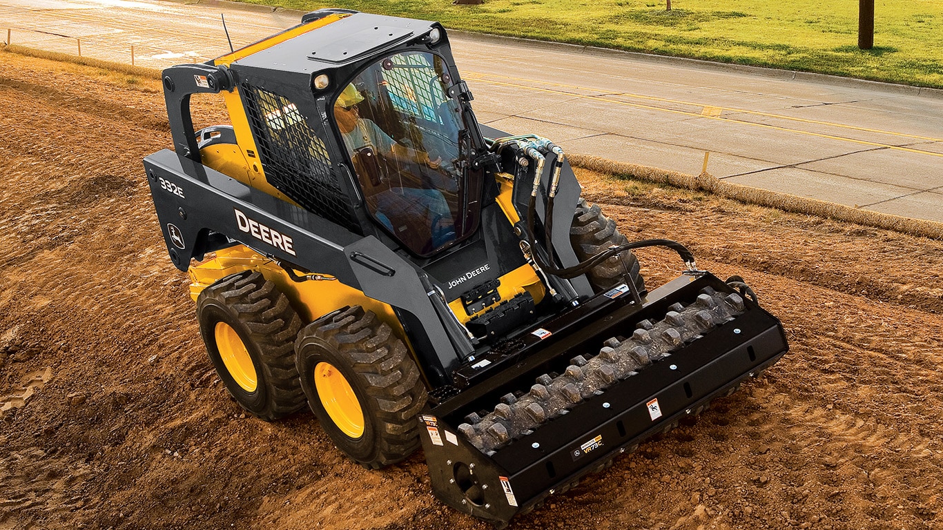 Skid Steer with vibratory roller attachment packing down dirt