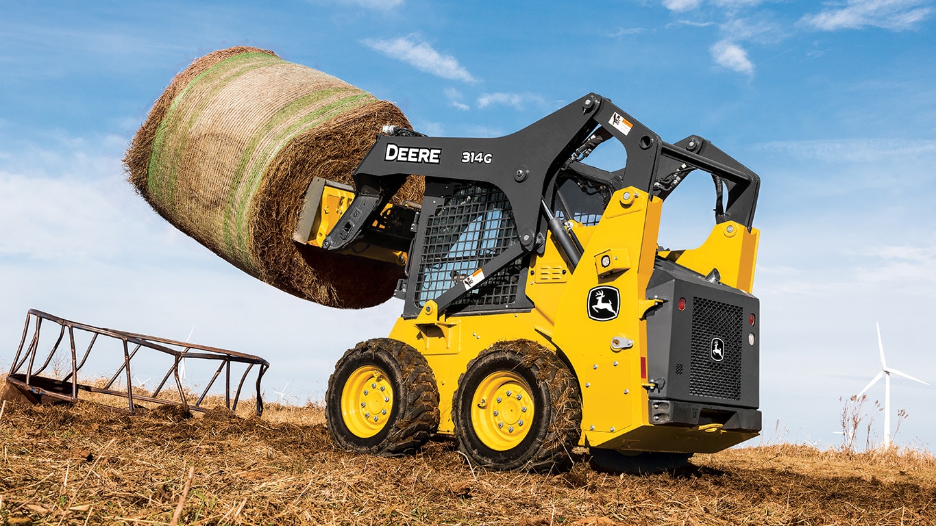 314G Skid Steer with bale spear attachment hauling a round bale.