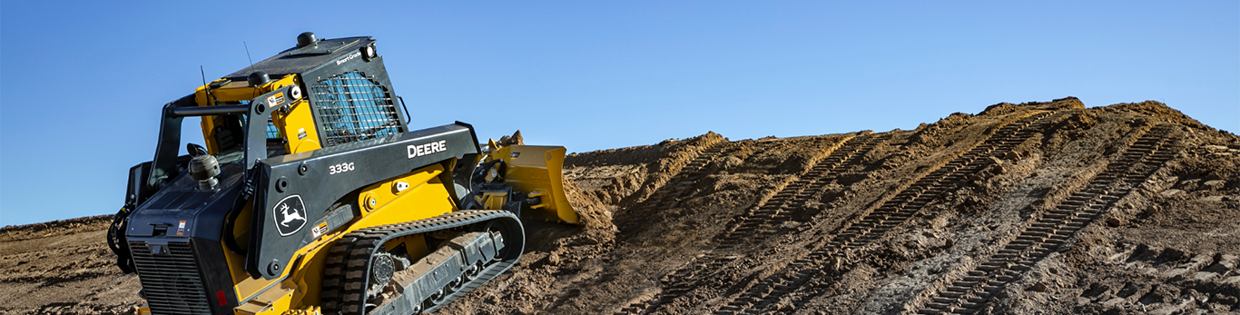 333G Skid Steer with tracks dozes up a hill of dirt