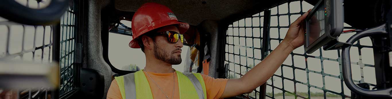 An operator works in the cab of a 333G SmartGrade Compact Track Loader