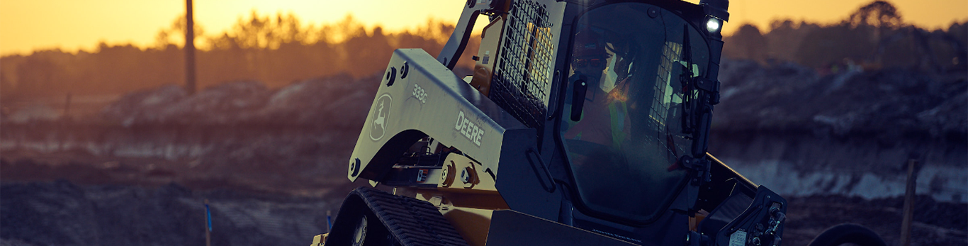 333G Compact tracked loader dozing a road ditch while the sun sets