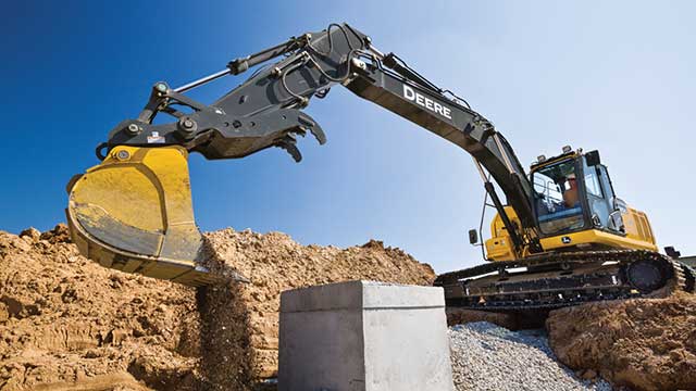 At a construction site, a John Deere excavator is being used to perform underground utility work.