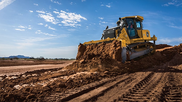 A John Deere dozer is moving dirt for roads and building pads at a housing development site.