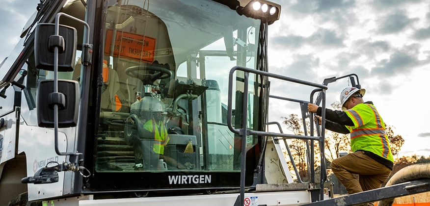 An equipment operator climbs up to the cab of Wirtgen KLEEMANN mobile jaw crusher.