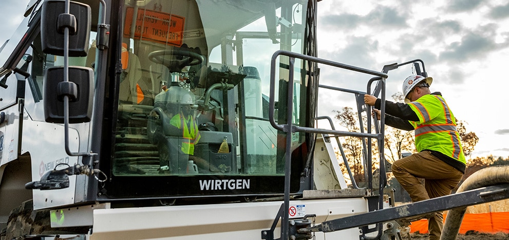An equipment operator climbs up to the cab of Wirtgen KLEEMANN mobile jaw crusher.