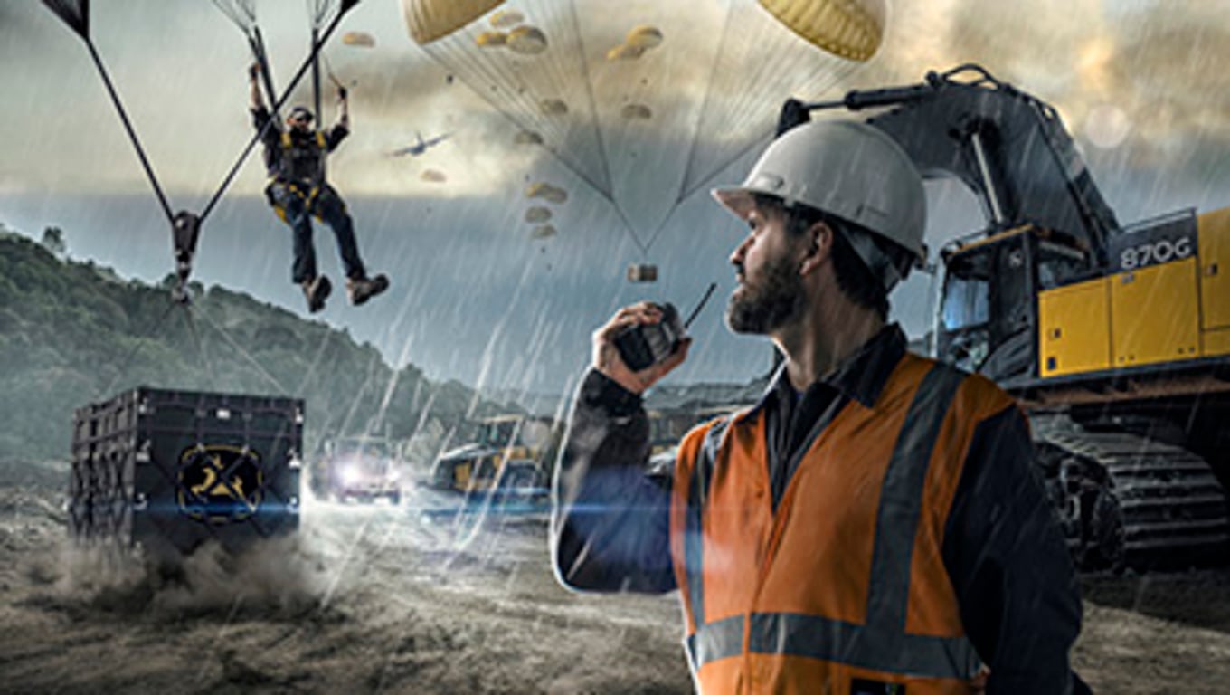 paratroopers delivering parts to a John Deere 870G excavator on a construction site in the rain.