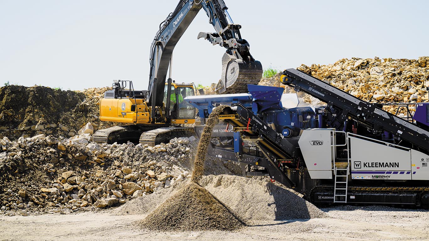 Excavator dumping crushed asphalt into a Kleemann mobile impact crusher