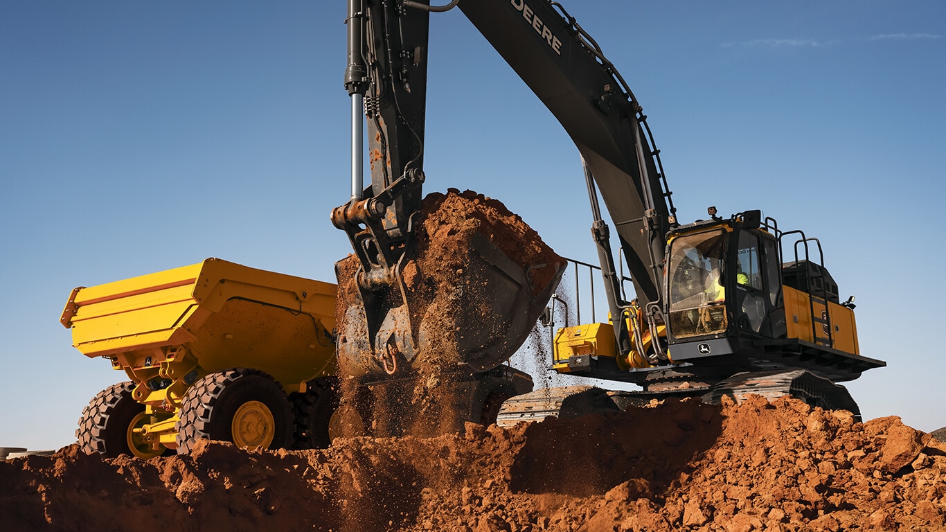 John Deere excavator moving dirt with bucket on job site.
