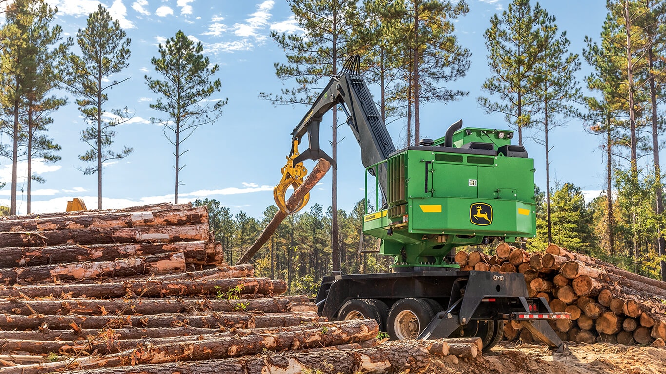 A John&nbsp;Deere knuckleboom loader moving logs on landing.