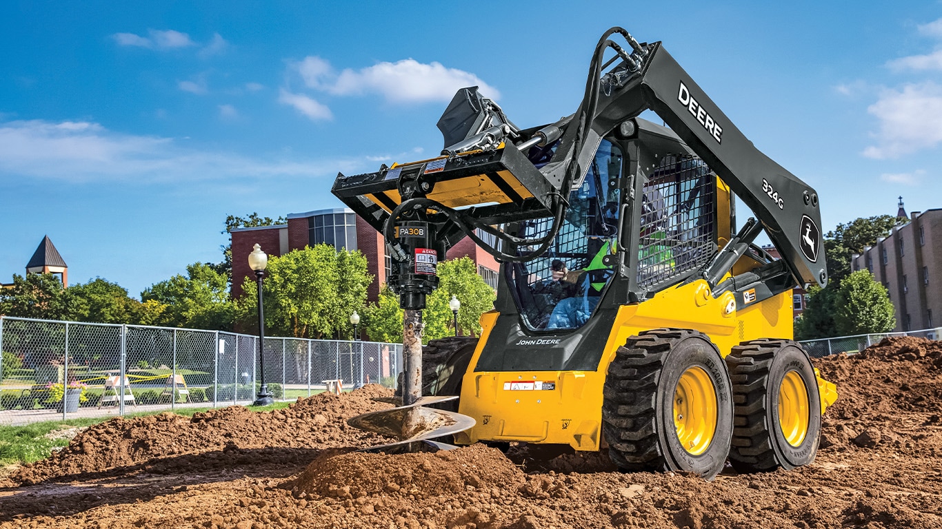John Deere 324G gap filler dumping dirt and gravel at a construction site.
