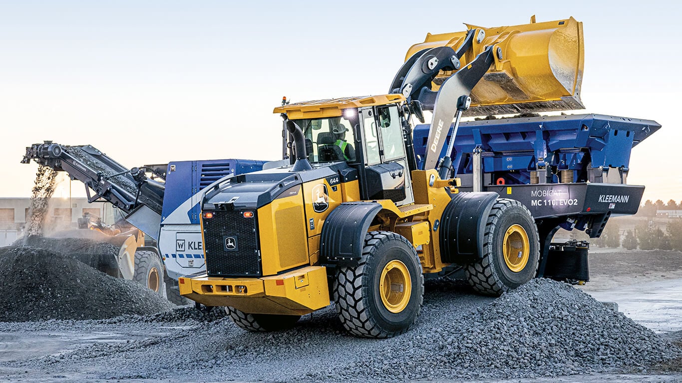 644 X-Tier wheel loader dumping rock into Kleemann mobile jaw crusher on work site.