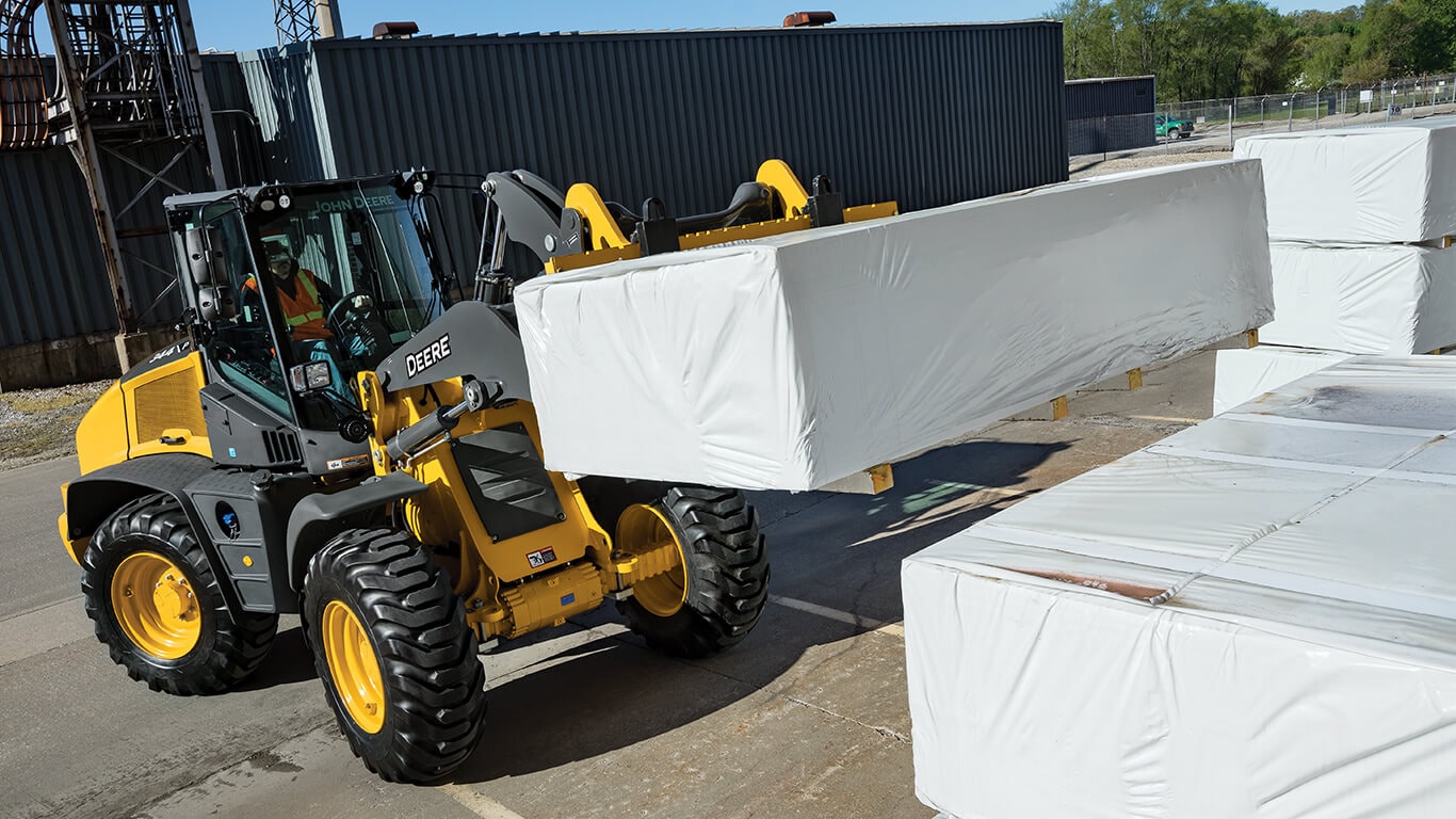 344 P-Tier wheel loader moving pallets with fork attachments.