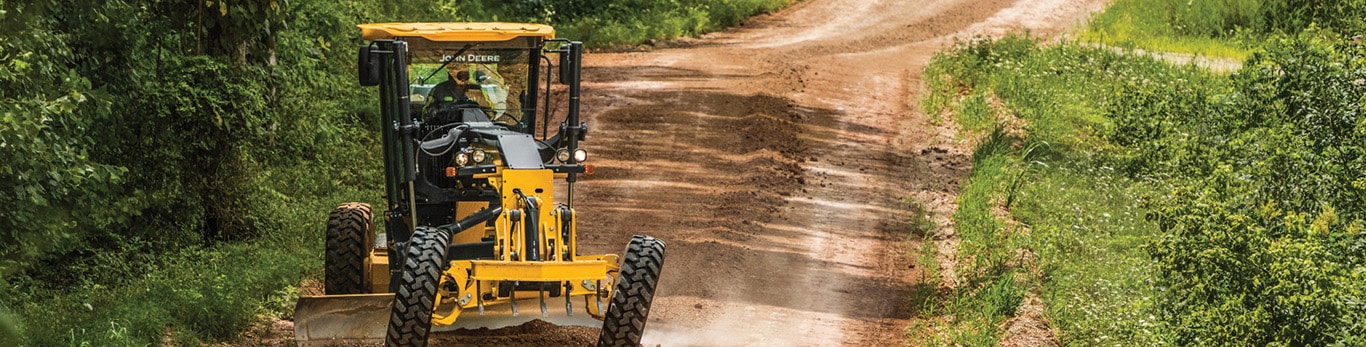 A John Deere Motor Grader works on a gravel road