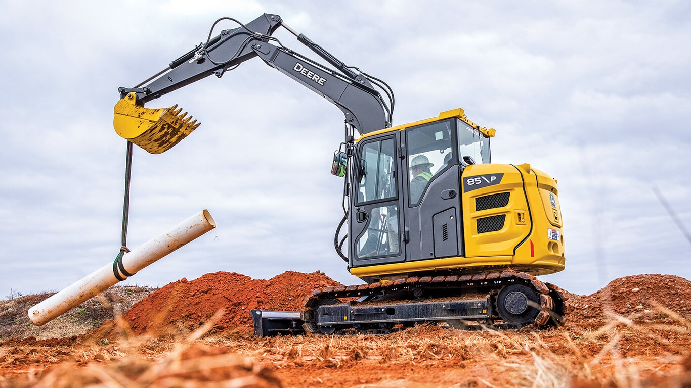 85 P-Tier excavator using bucket to lift pipe on job site.