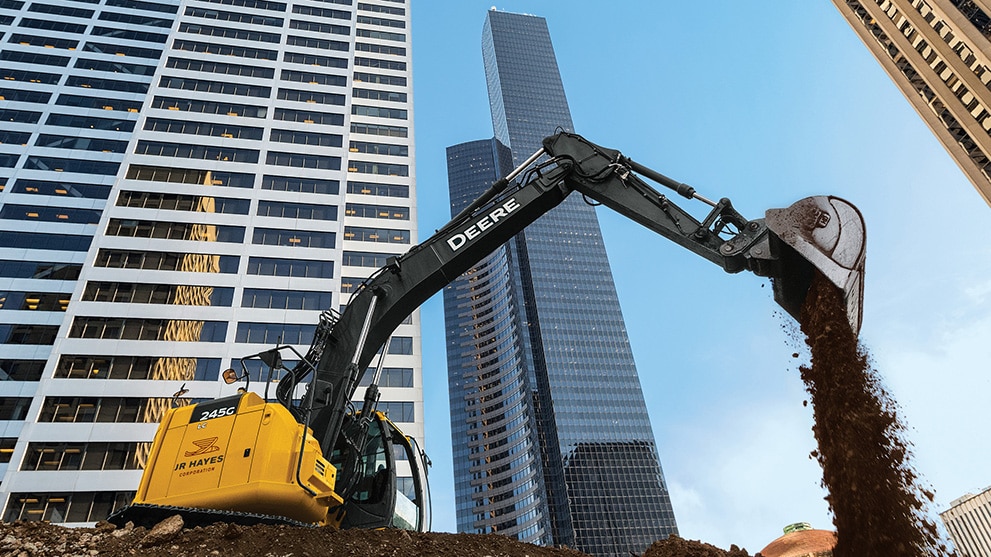 Working excavator against a city skyline