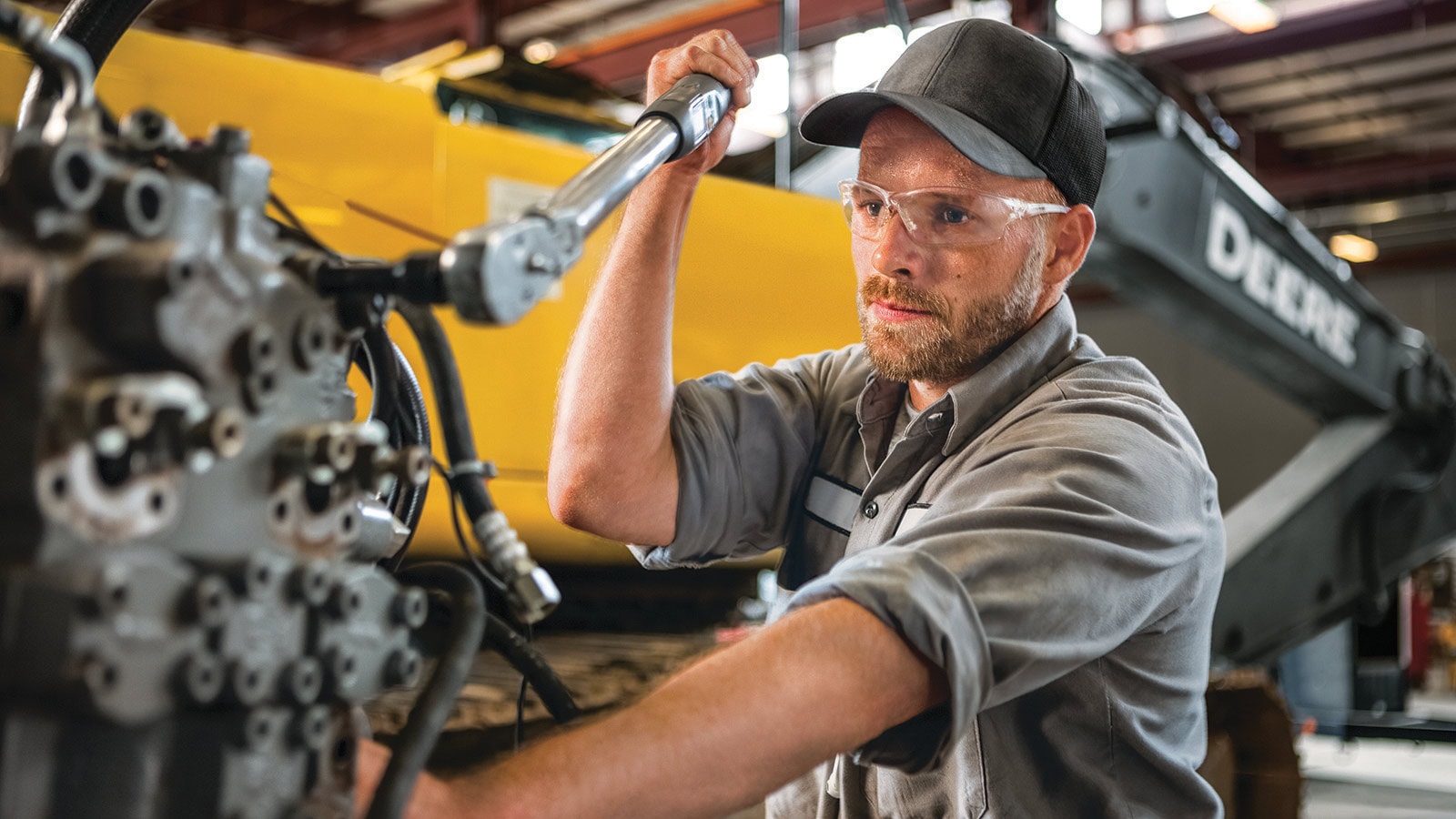 A factory worker works on a piece of construction equipment