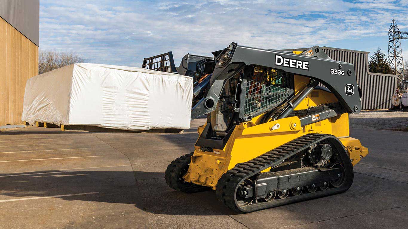 John Deere 333G Compact Track Loader with Worksite Pro Pallet Forks lifting a load.