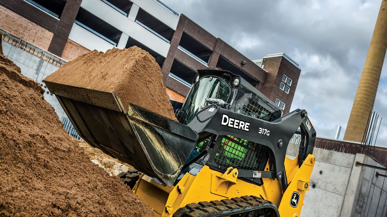 A 317G lifts a full bucket of dirt on a jobsite.