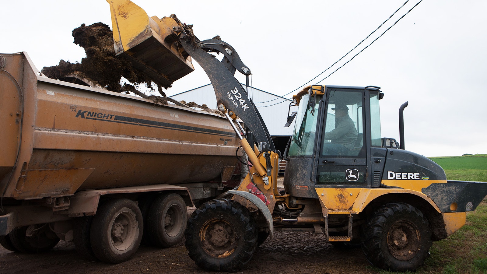 324K High-Lift loader loads a feed mixer