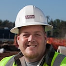 Construction worker in a white hardhat with work site in the background