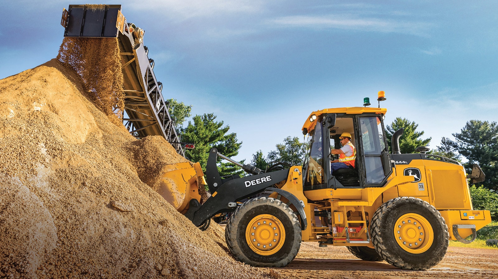 444L Wheel Loader scoops up a load of material from a pile coming off a conveyor belt