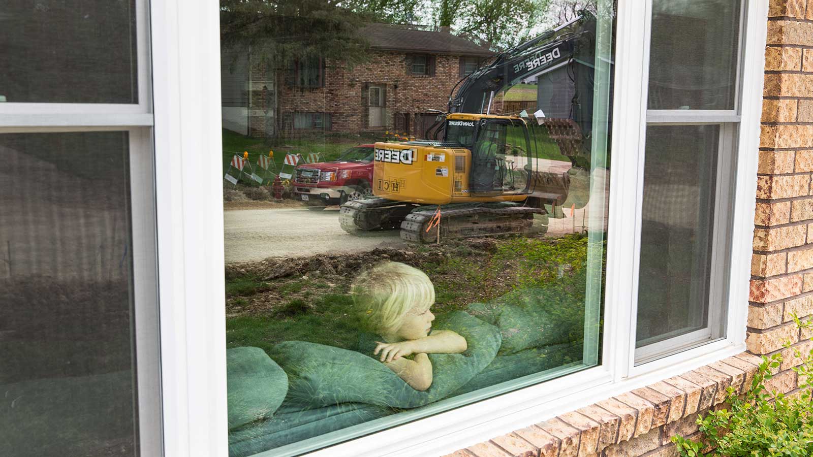 Charlie Koelker watches the work from the window inside his home.