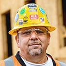 A head shot of Tim Orozco wearing a hard hat and eye protection.