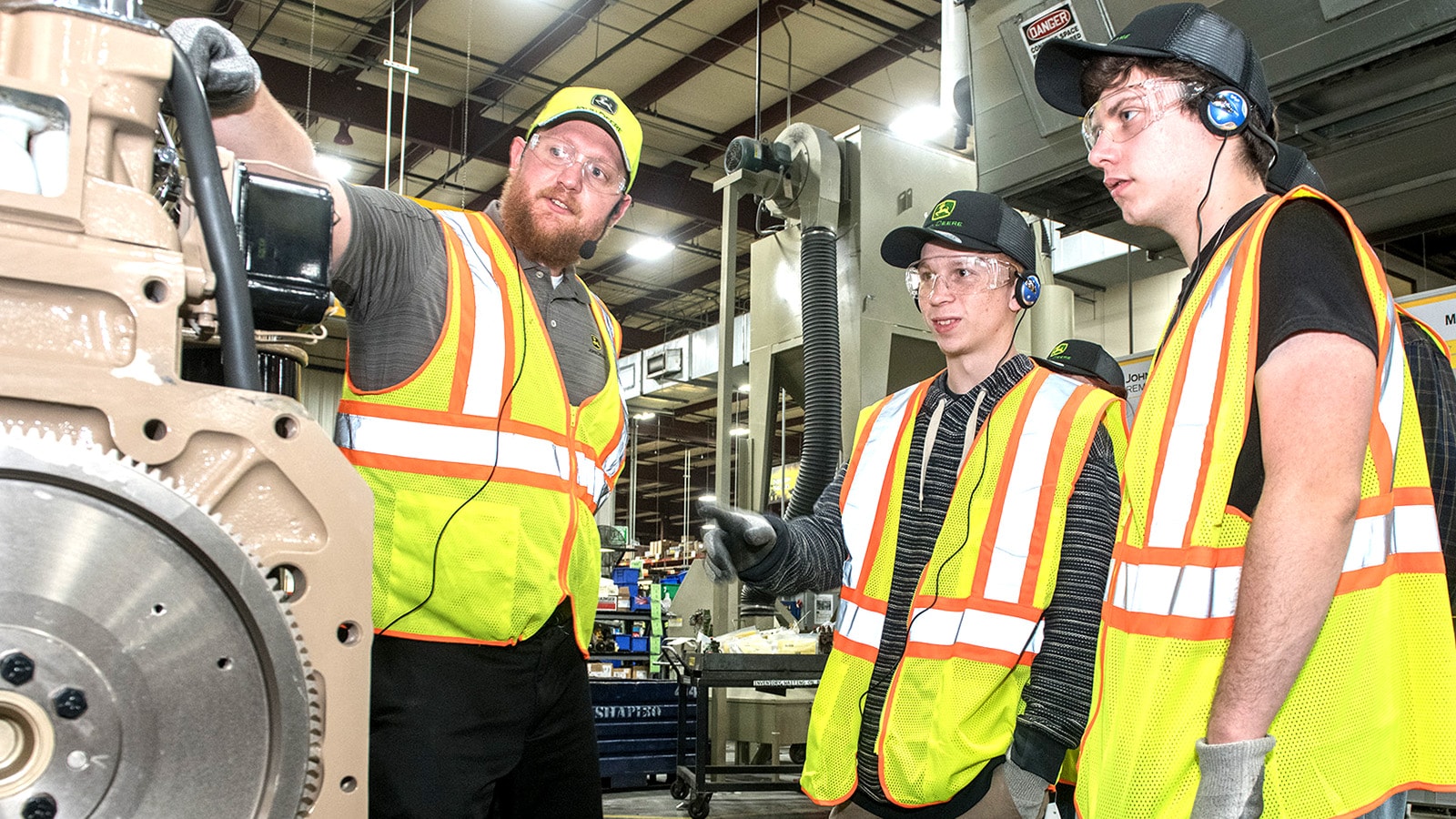 Students listen to their tour guide pointing at a remanufactured component in the Springfield facility 