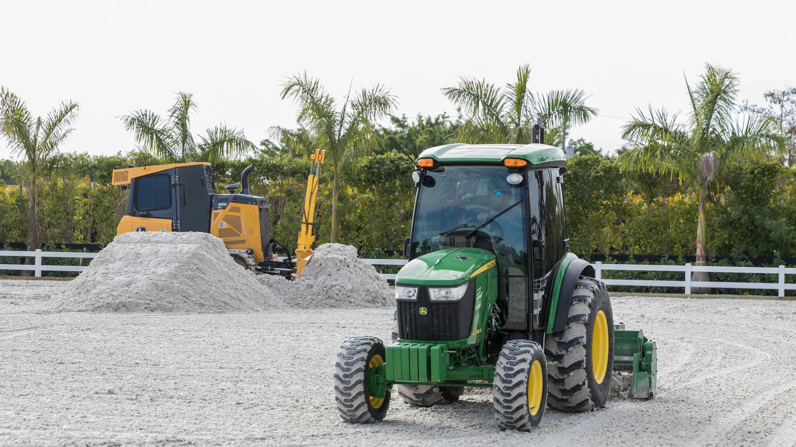 4066R Compact Tractor and 450K Dozer work in a horse ring together, laying down material