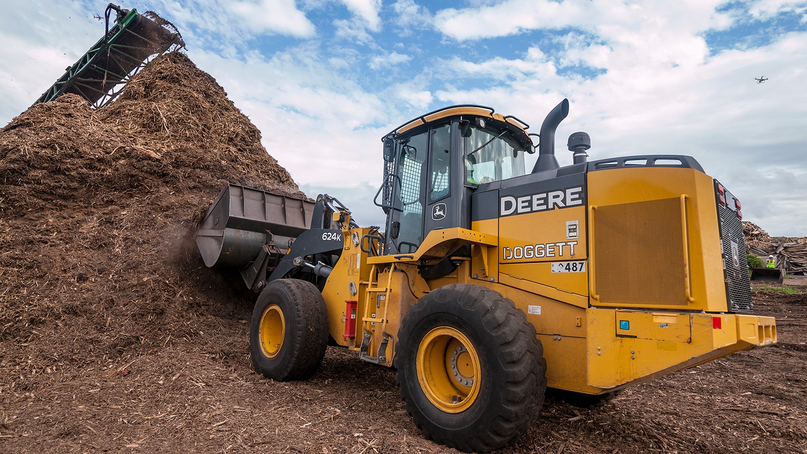 624K wheel loader scoops up a bucket load of mulch from a large pile