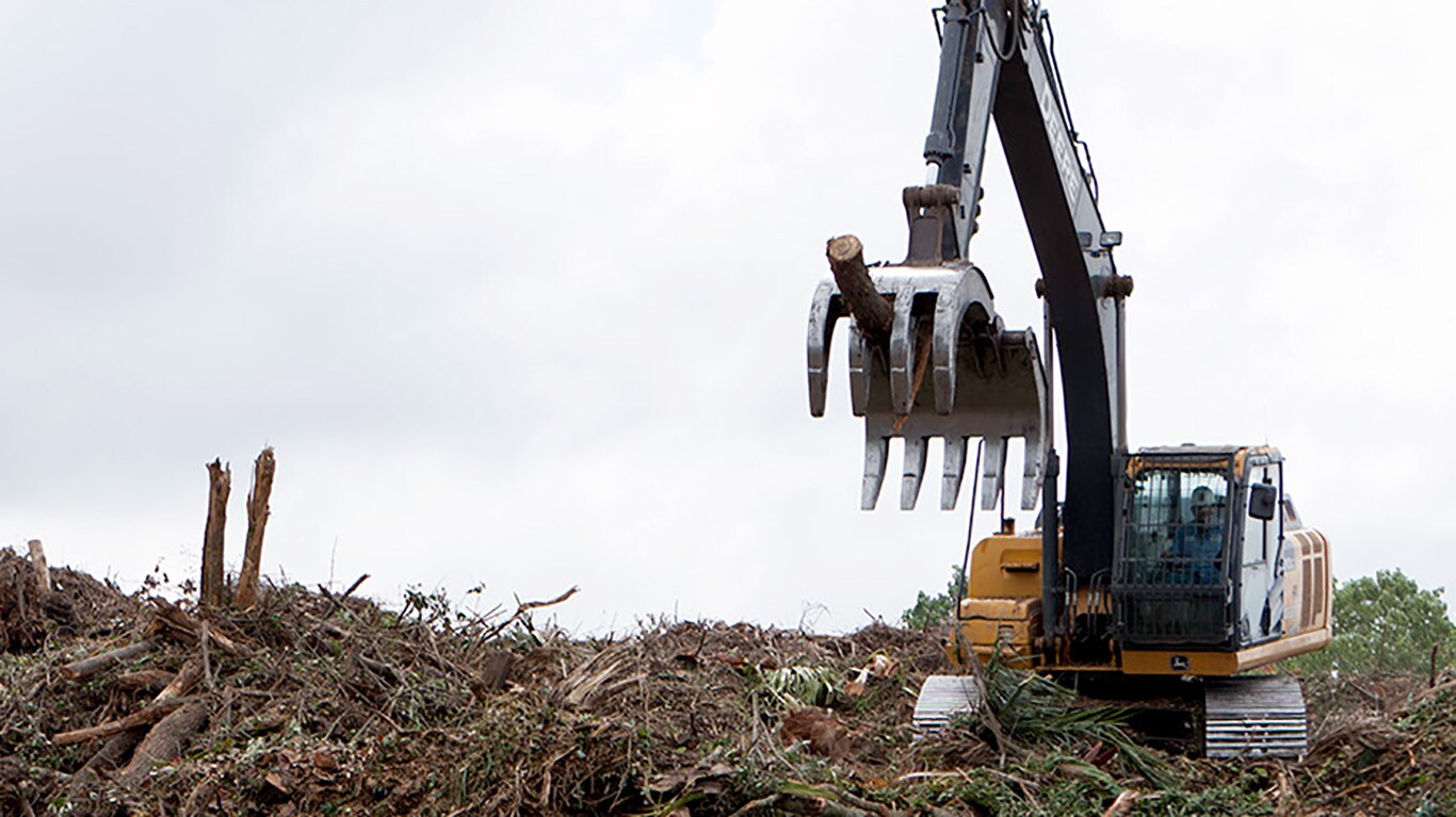 An excavator sorts through a pile of scrap wood