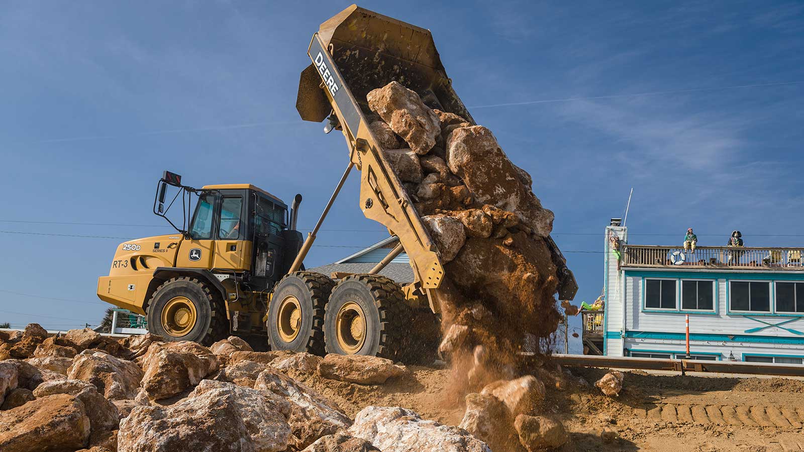 250D Dump Truck dumping a load of boulders on the beach