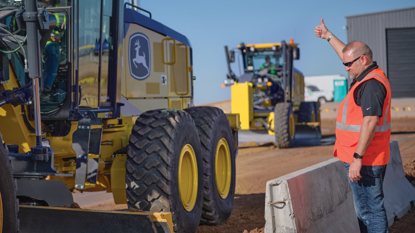 Operator evaluating grade during a training exercise using John Deere motor graders.