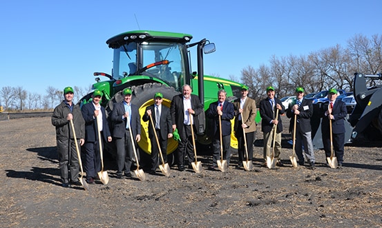 A group of men with shovels in front of a John Deere tractor