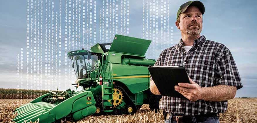 Man holding tablet standing in front of S780 combine in a corn field
